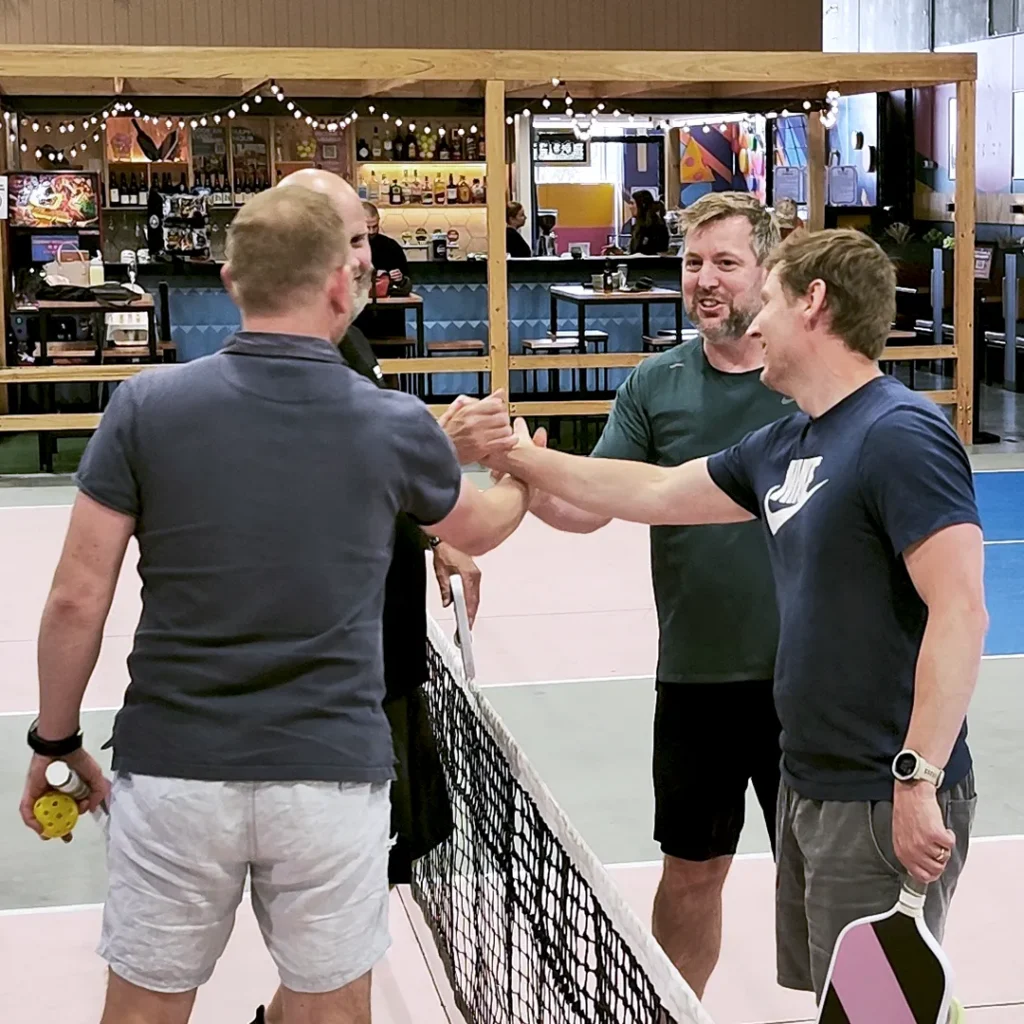 Staff shaking hands during a friendly pickle ball match
